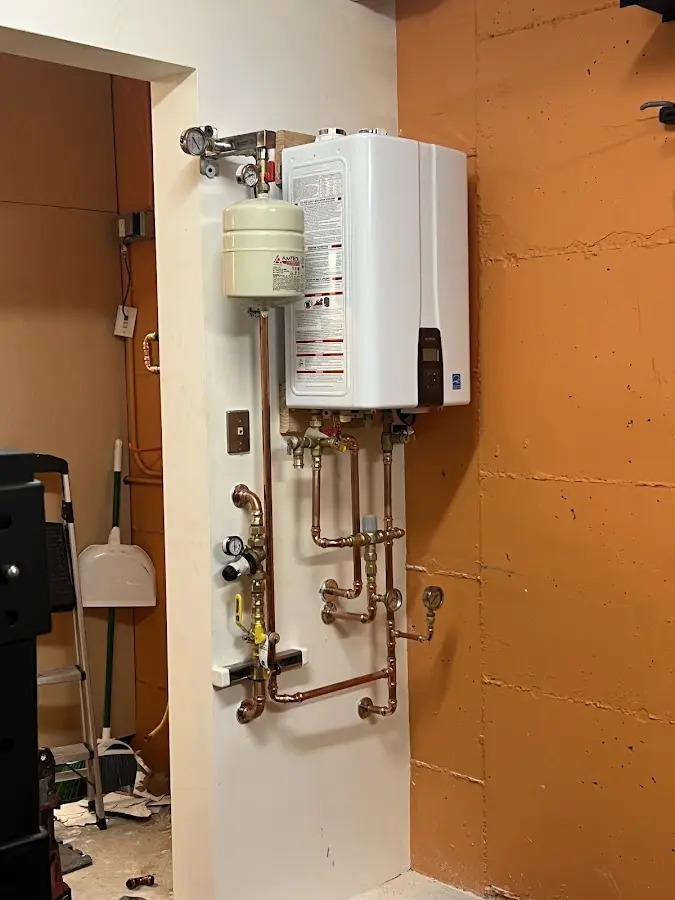 Plumbing technician inspecting water heater connections in Suffern